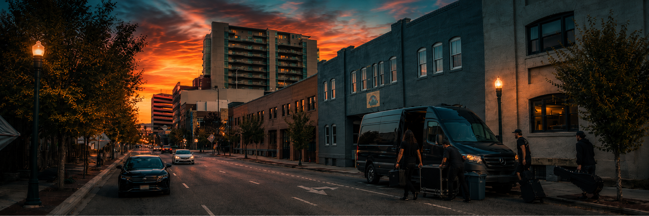 Crew unloading gear from a van outside a downtown venue at sunset